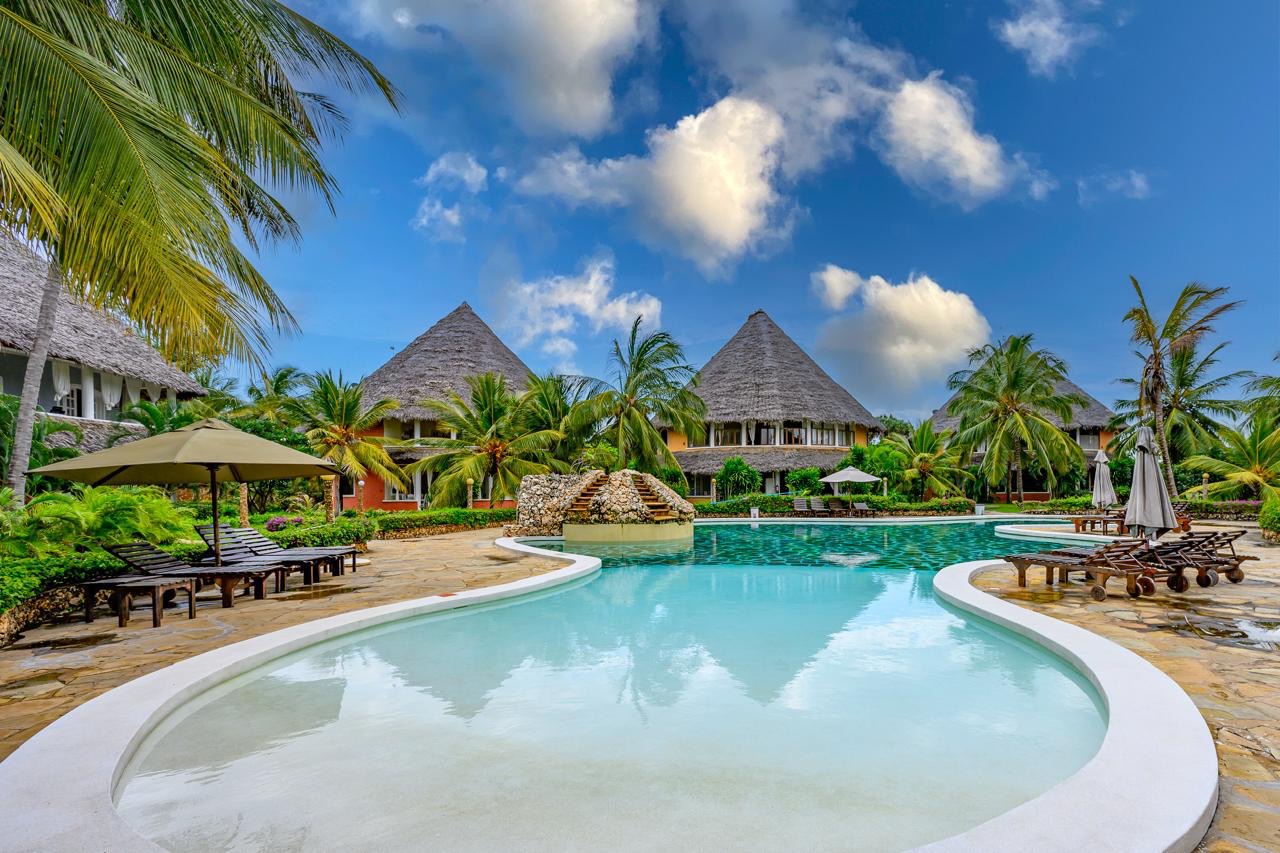 Resort swimming pool surrounded by tropical palms and sun loungers