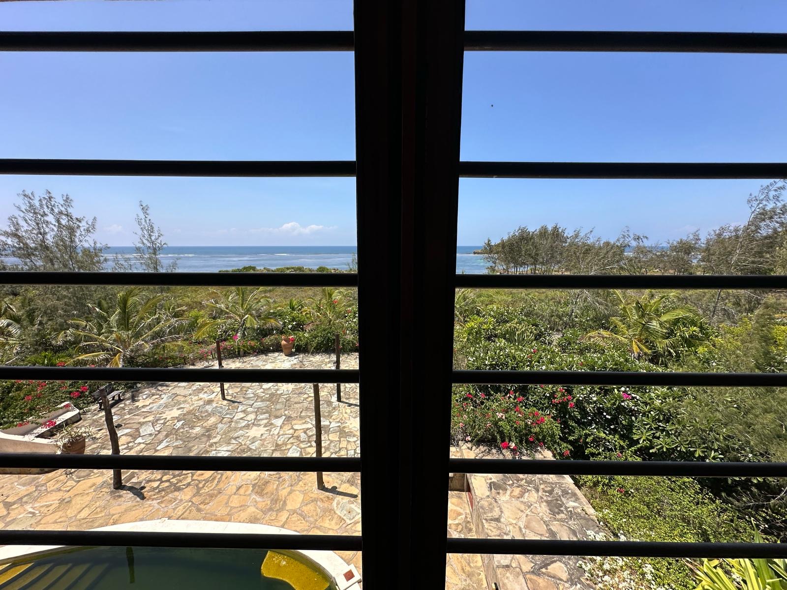 Ocean and garden view through a bedroom window
